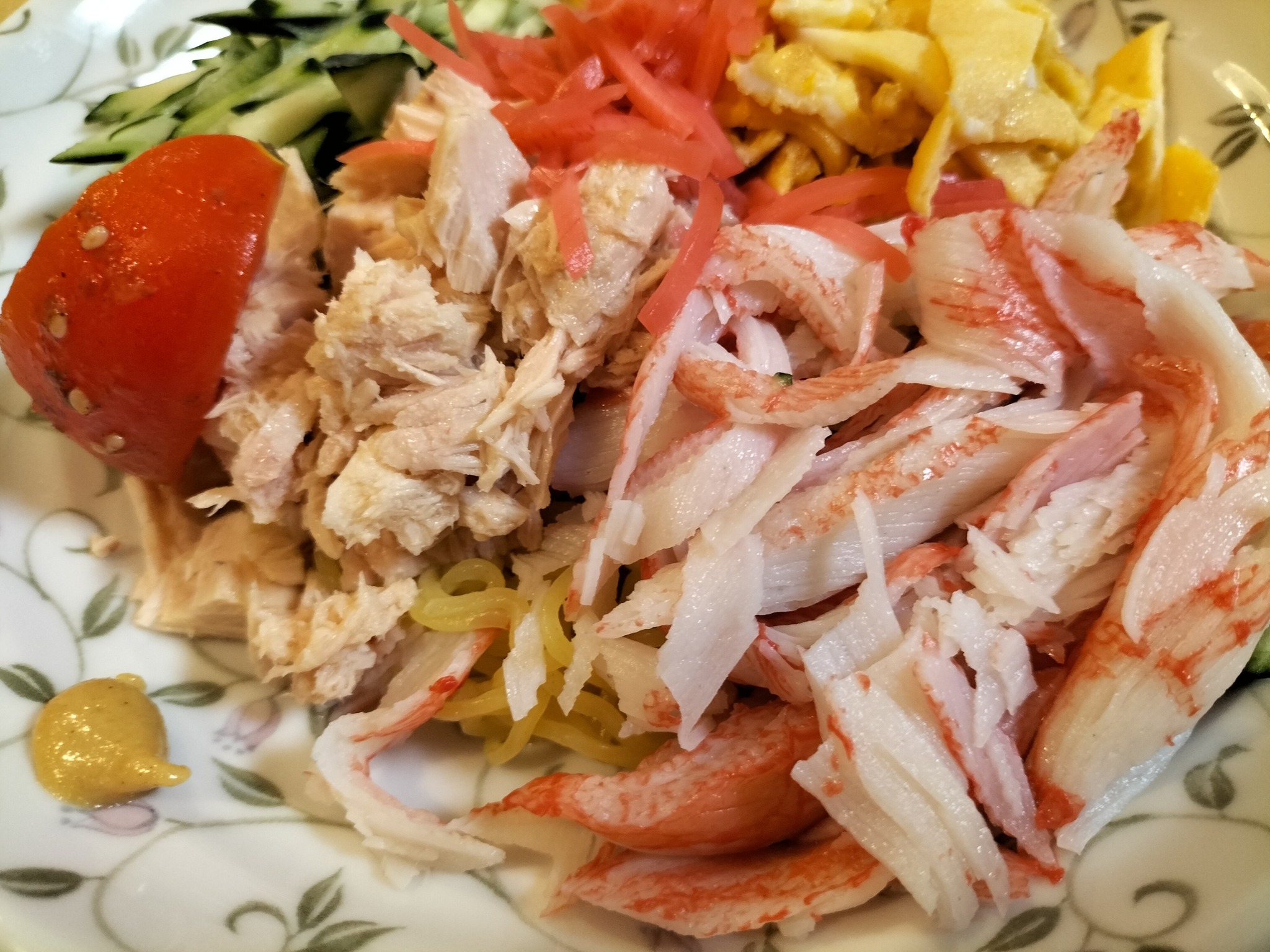 定番具材の錦糸卵、とまと、きゅうりにハムの代わりにシーチキンとカニカマをトッピングした具だくさんの冷やし中華