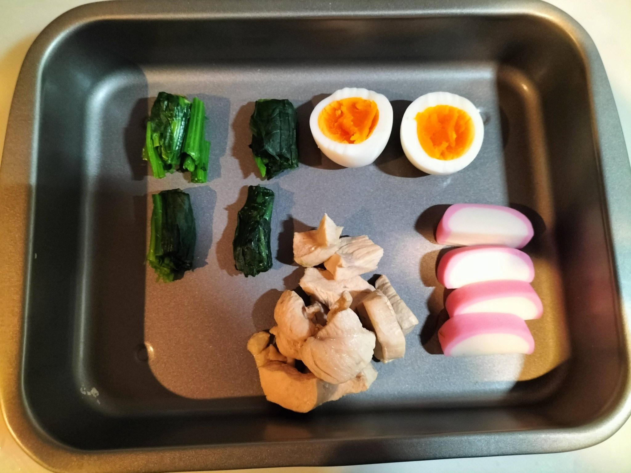 鍋焼きうどんの具材の鶏ムネ肉、ゆで卵、かまぼこ、ほうれん草