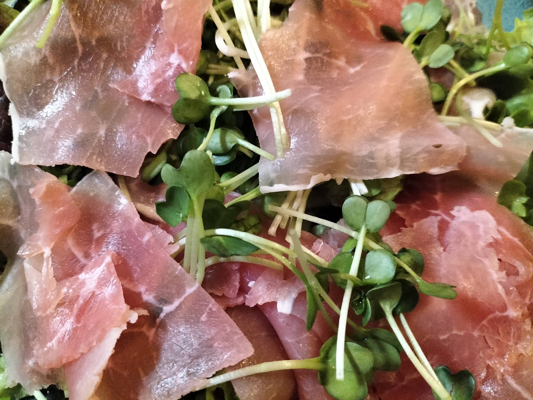 新鮮なリーフレタス、カイワレの上に、薄切りの生ハムをトッピングした生ハムサラダ